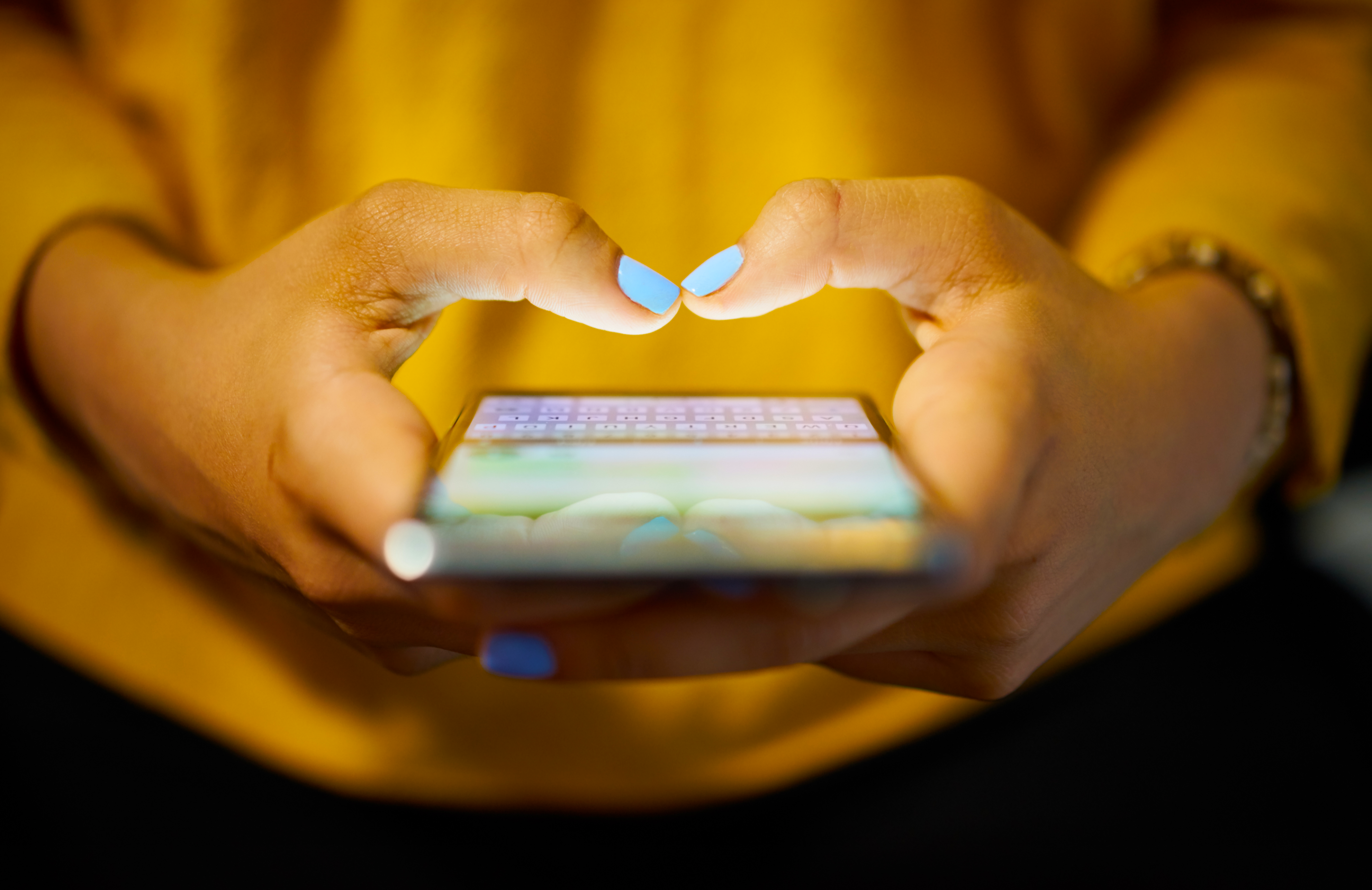 Young lady in yellow jumper typing on her phone